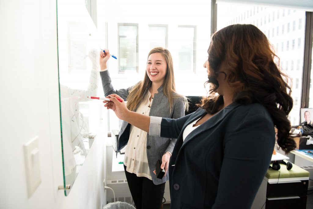 two-women-in-front-of-dry-erase-board-1181533